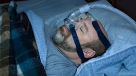 Male patient asleep in bed with CPAP mask