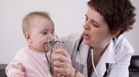 Female doctor holding an oxygen mask from nebuliser to a a baby's face