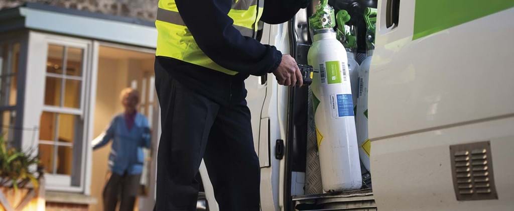 Technician scanning oxygen cylinder before delivering to a patient at home